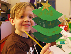 Junge zeigt selbst gebastelten Papiertannenbaum